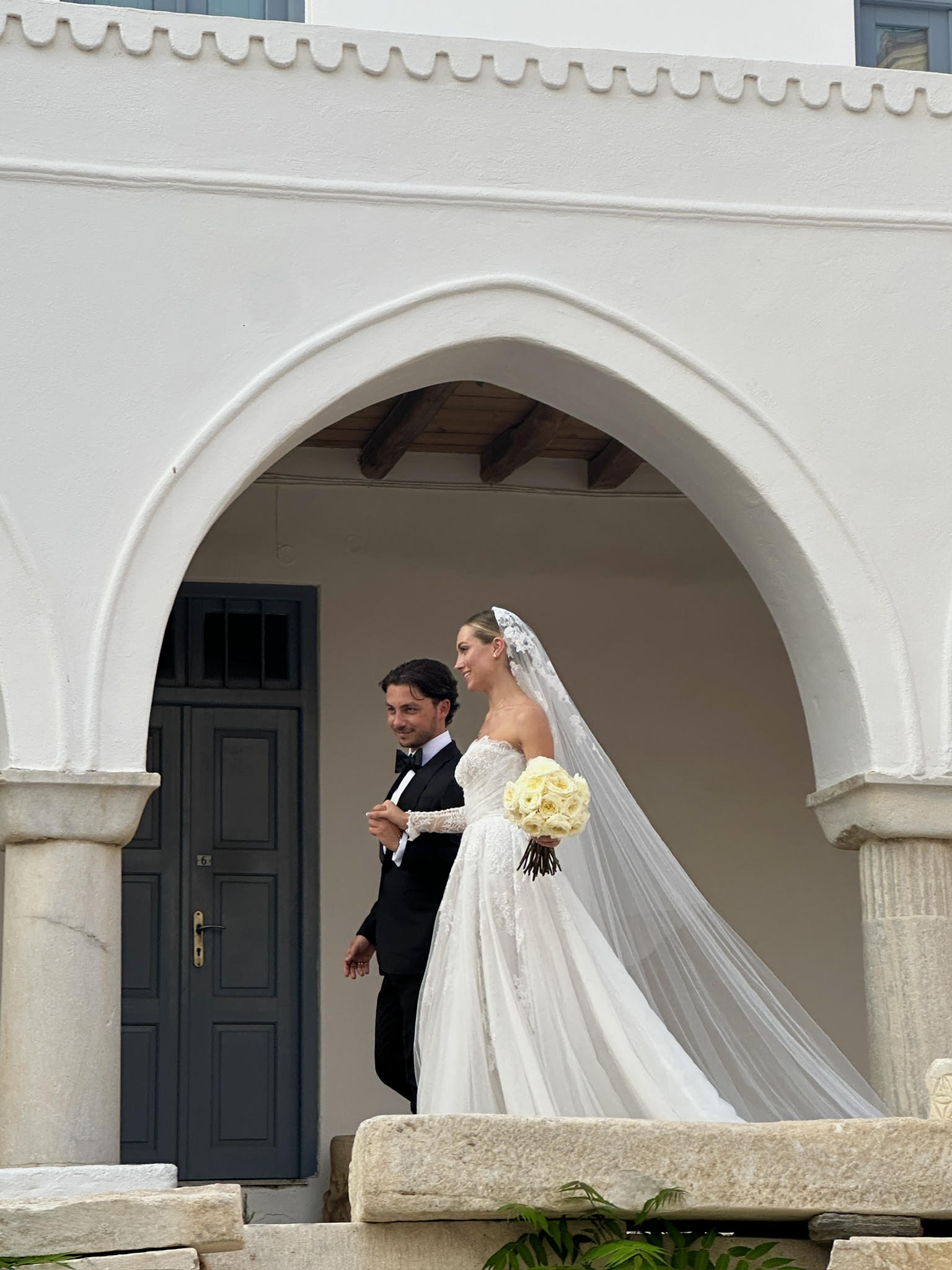 A bride and groom beneath a whitewashed archway